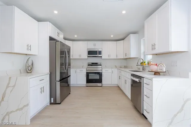 a kitchen with granite countertop white cabinets and stainless steel appliances