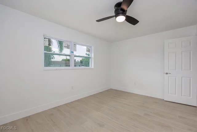 a view of an empty room with a window and wooden floor