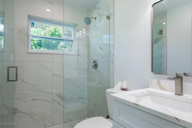 a bathroom with a granite countertop sink a toilet and shower