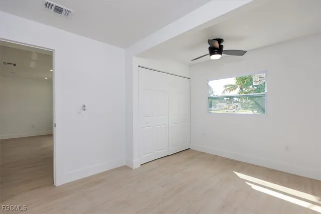 an empty room with windows and ceiling fan