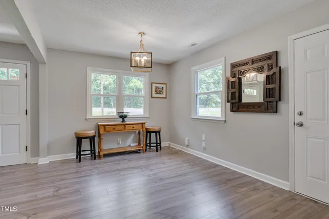 an empty room with wooden floor cabinet and windows