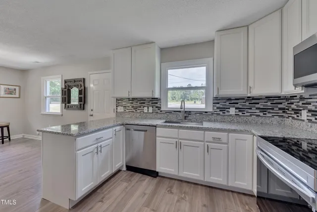 a kitchen with white cabinets sink and appliances