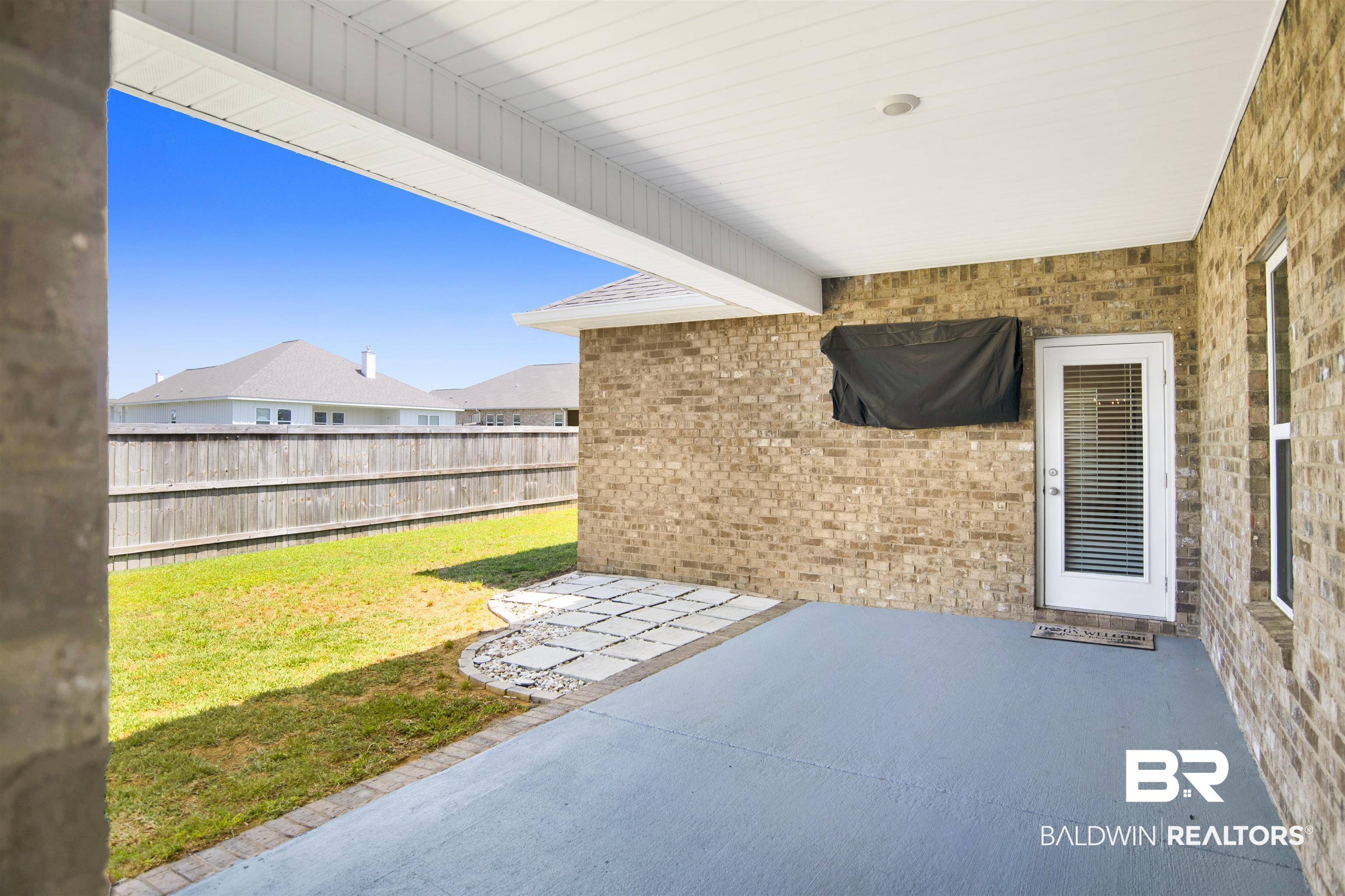 8493 Bronze Lane Foley, AL 36535 - Photo 30 of 38 Covered patio with a painted concrete floor, brick exterior, and white glass-paned door
