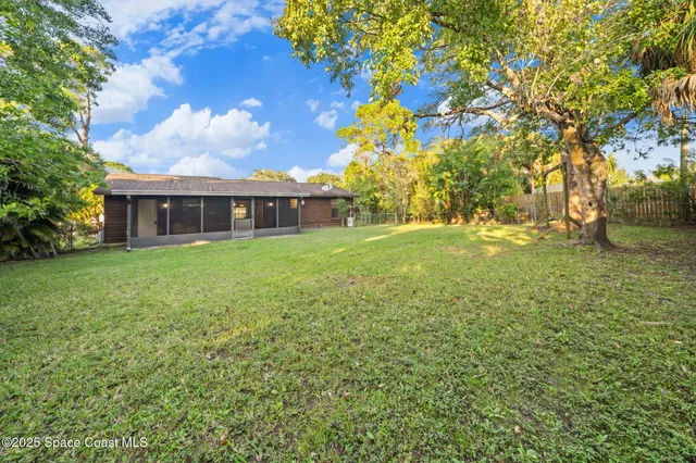 a view of a house with a big yard and large trees
