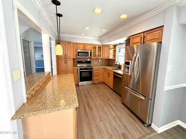 a kitchen with stainless steel appliances granite countertop a refrigerator a stove and a wooden floor