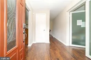 a view of a hallway with wooden floor and a bathroom