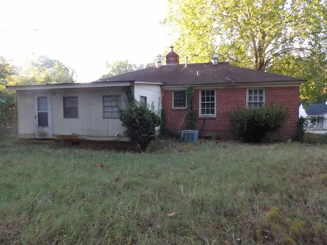 a view of a yard in front of a house with plants and large tree