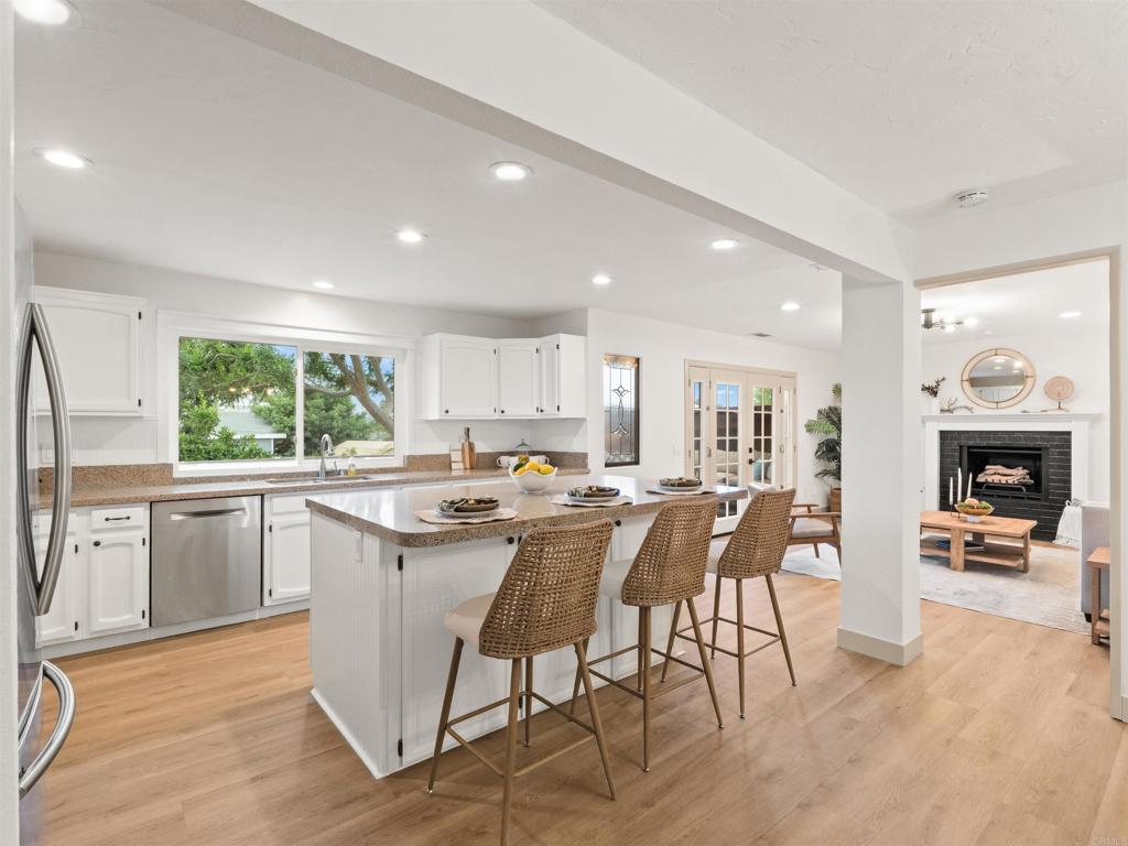 13737 Temple Street Poway, CA 92064 - Photo 13 of 38 a dining hall with stainless steel appliances granite countertop a stove top oven a sink dishwasher a dining table and chairs with wooden floor