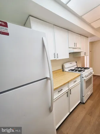 a kitchen with a refrigerator a stove top oven and white cabinets