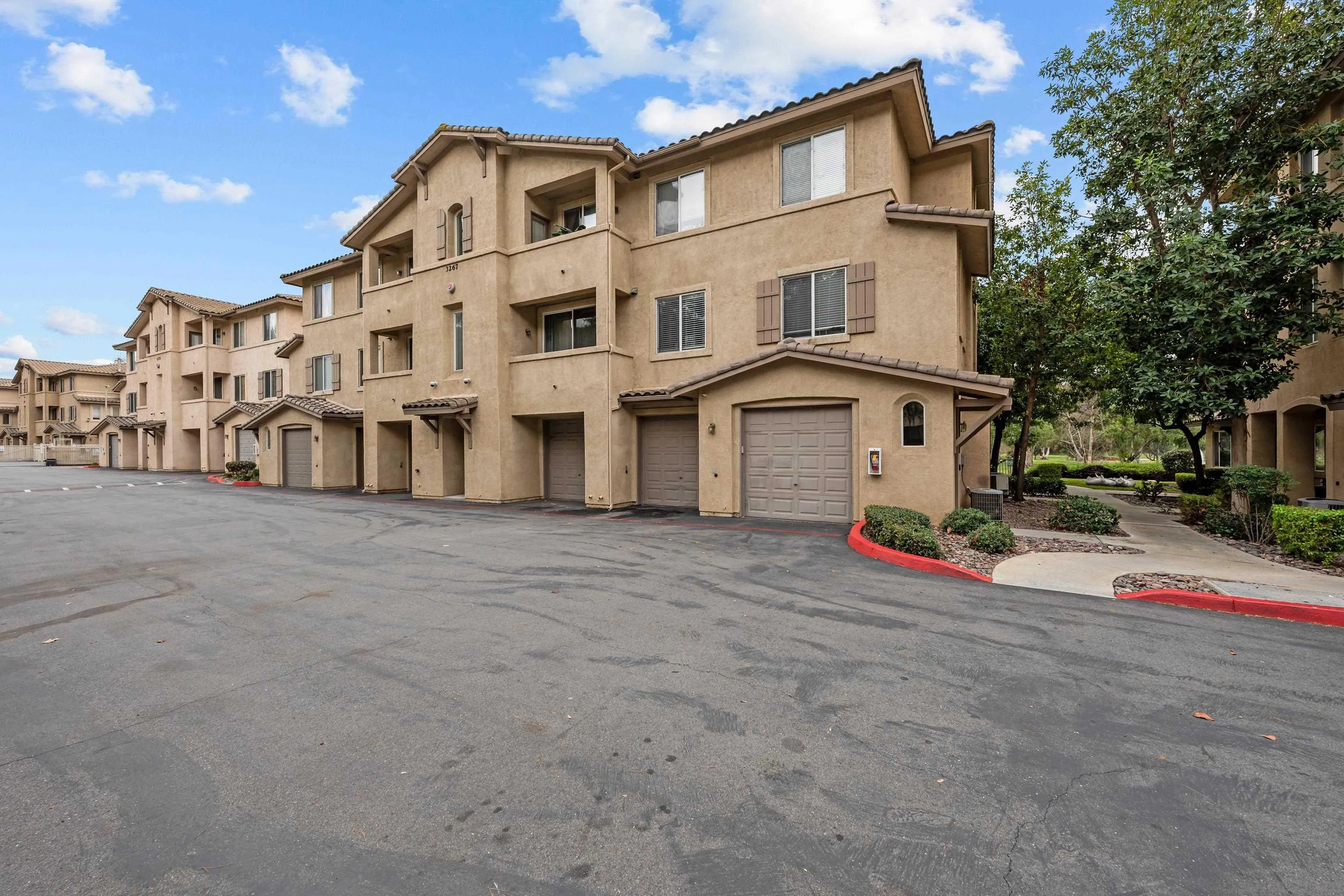3267 Dehesa Road, Unit 69 El Cajon, CA 92019 - Photo 5 of 34 a view of a white house with large windows and a table and chairs under an umbrella
