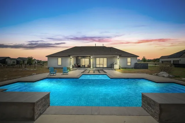 a view of swimming pool with lawn chairs and a table