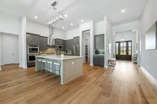 a large kitchen with cabinets wooden floor and stainless steel appliances