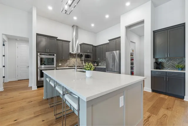 a large kitchen with stainless steel appliances kitchen island granite countertop a refrigerator and a stove top oven