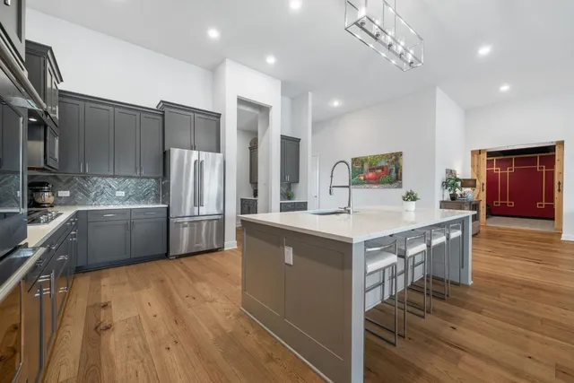 a kitchen with stainless steel appliances granite countertop a refrigerator a stove and a wooden floors