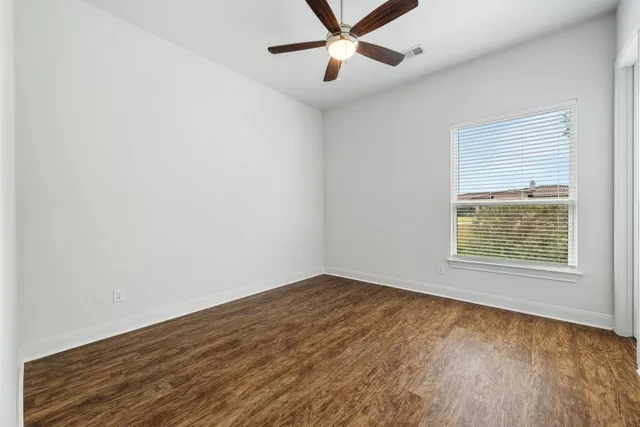 an empty room with a window and a ceiling fan