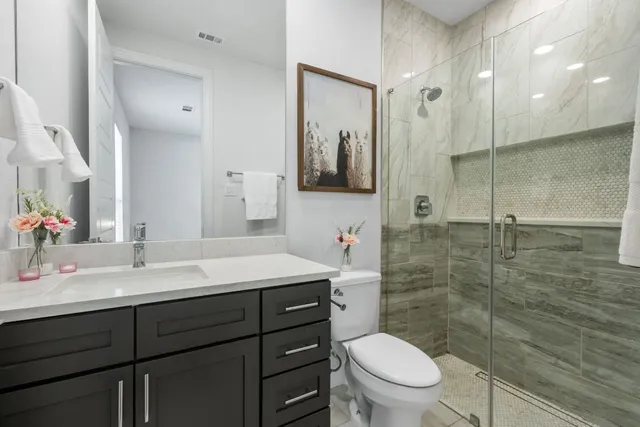 a bathroom with a toilet a sink a mirror and shower