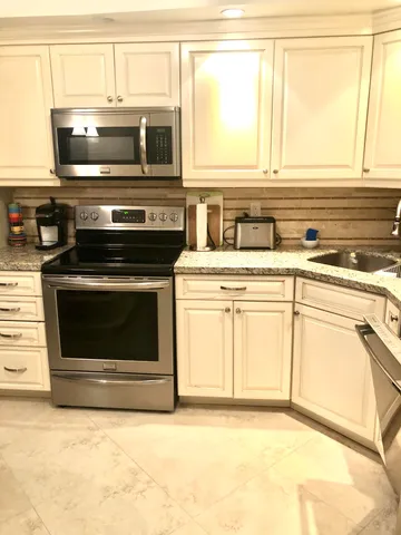 a kitchen with granite countertop a stove top oven microwave and cabinets