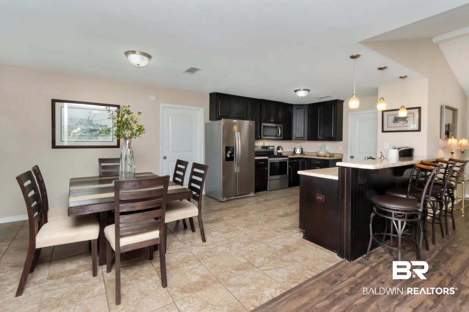 11528 Mocking Bird Lane Fairhope, AL 36532 - Photo 13 of 45 Kitchen with dark cabinets, stainless steel appliances, a peninsula, a breakfast bar, and decorative light fixtures