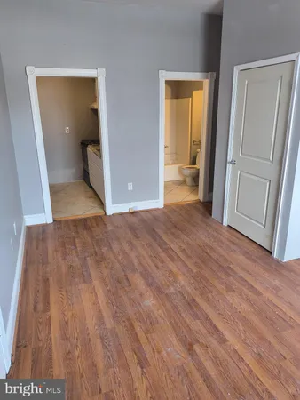 an empty room with wooden floor and a bathroom