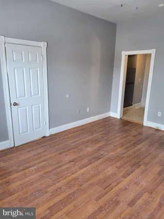 a view of an empty room with wooden floor and closet