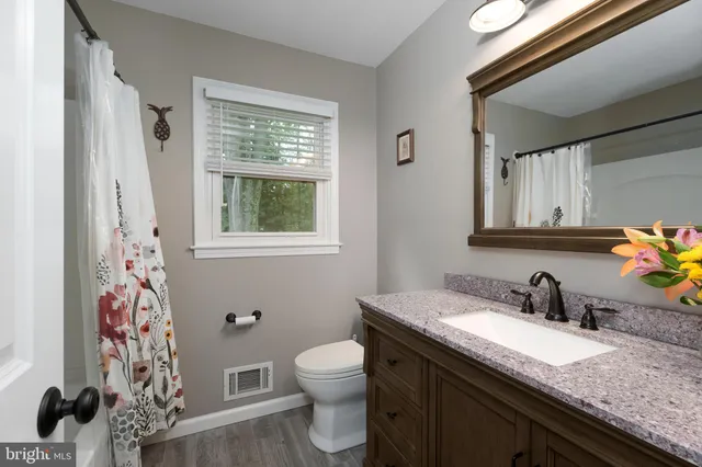 a bathroom with a granite countertop bathtub sink vanity mirror and toilet