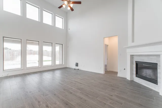 an empty room with wooden floor fireplace and windows