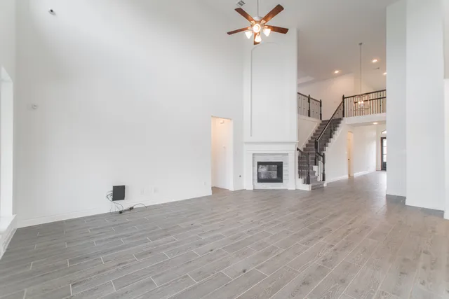 a view of a livingroom with wooden floor a ceiling fan and a fireplace