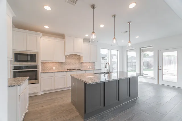 a large kitchen with granite countertop a stove top oven a sink a dining table and chairs