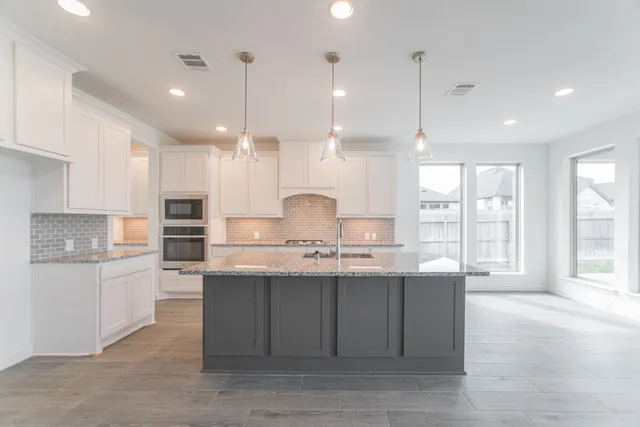 a large kitchen with kitchen island a sink a center island stainless steel appliances and a window