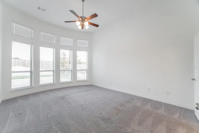 an empty room with chandelier fan and windows