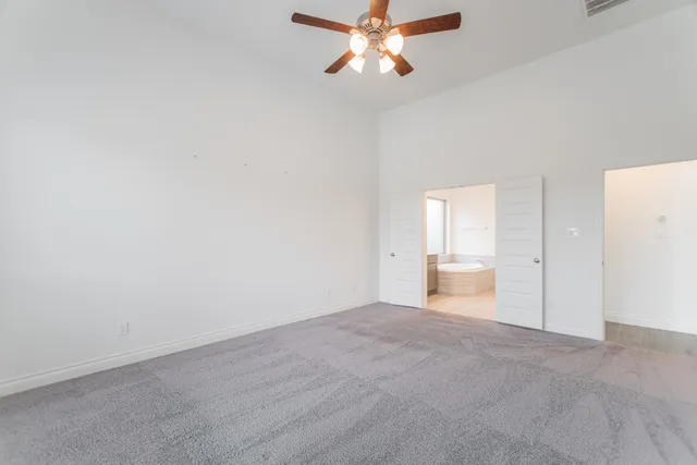 a view of an empty room and chandelier fan
