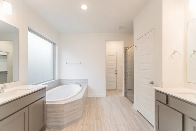 a spacious bathroom with a granite countertop sink a mirror and a bathtub