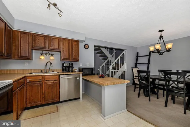 a dining room with stainless steel appliances granite countertop furniture and a chandelier