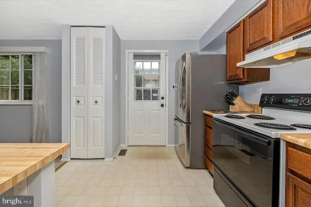 a dining room with stainless steel appliances granite countertop a refrigerator a sink dishwasher a dining table and chairs with wooden floor