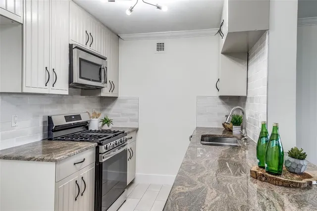 a kitchen with stainless steel appliances granite countertop a sink a stove and cabinets