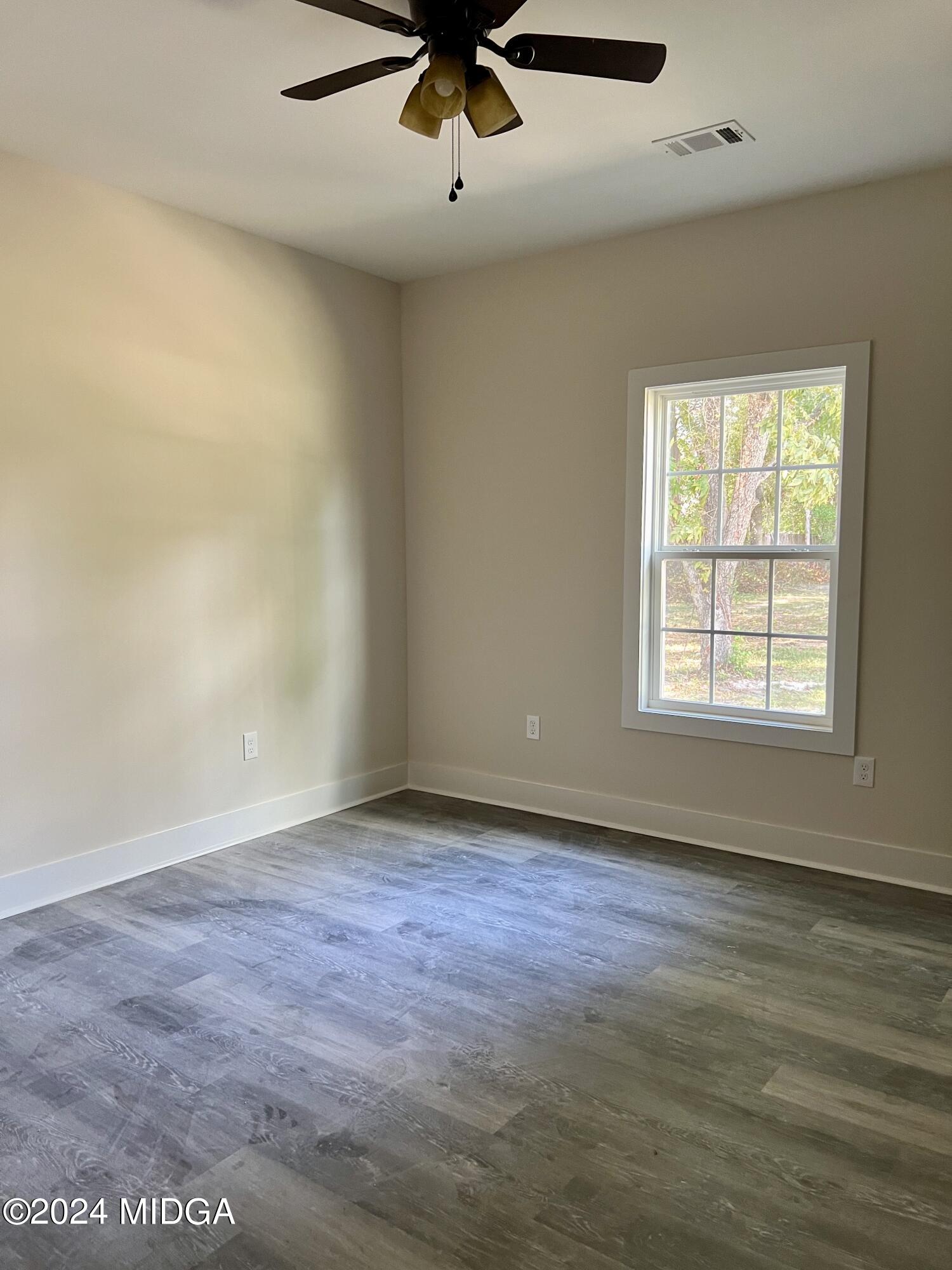 450 Walker Road Byron, GA 31008 - Photo 14 of 22 an empty room with wooden floor chandelier fan and windows