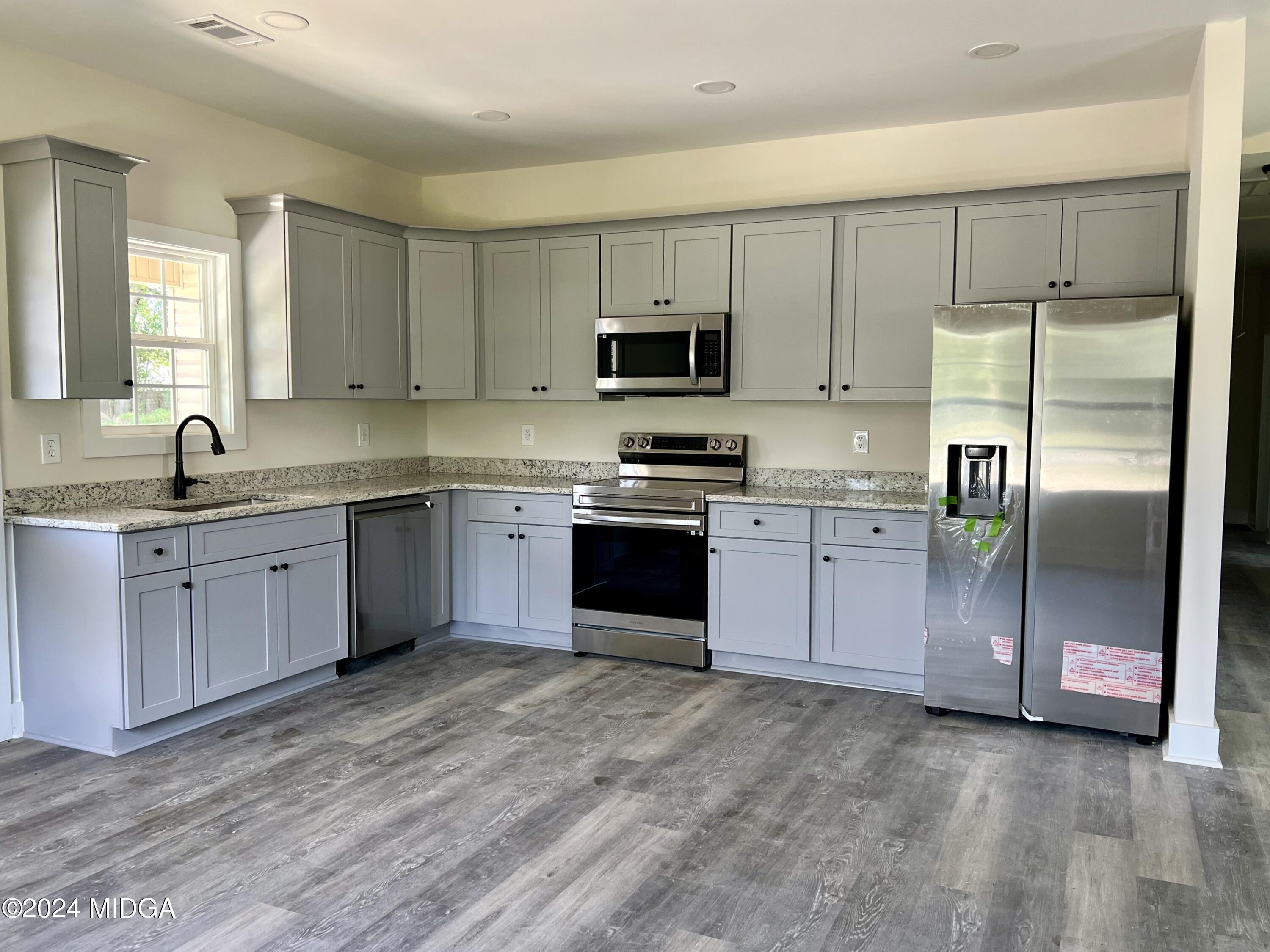 450 Walker Road Byron, GA 31008 - Photo 4 of 22 a kitchen with stainless steel appliances granite countertop a stove a sink and a refrigerator
