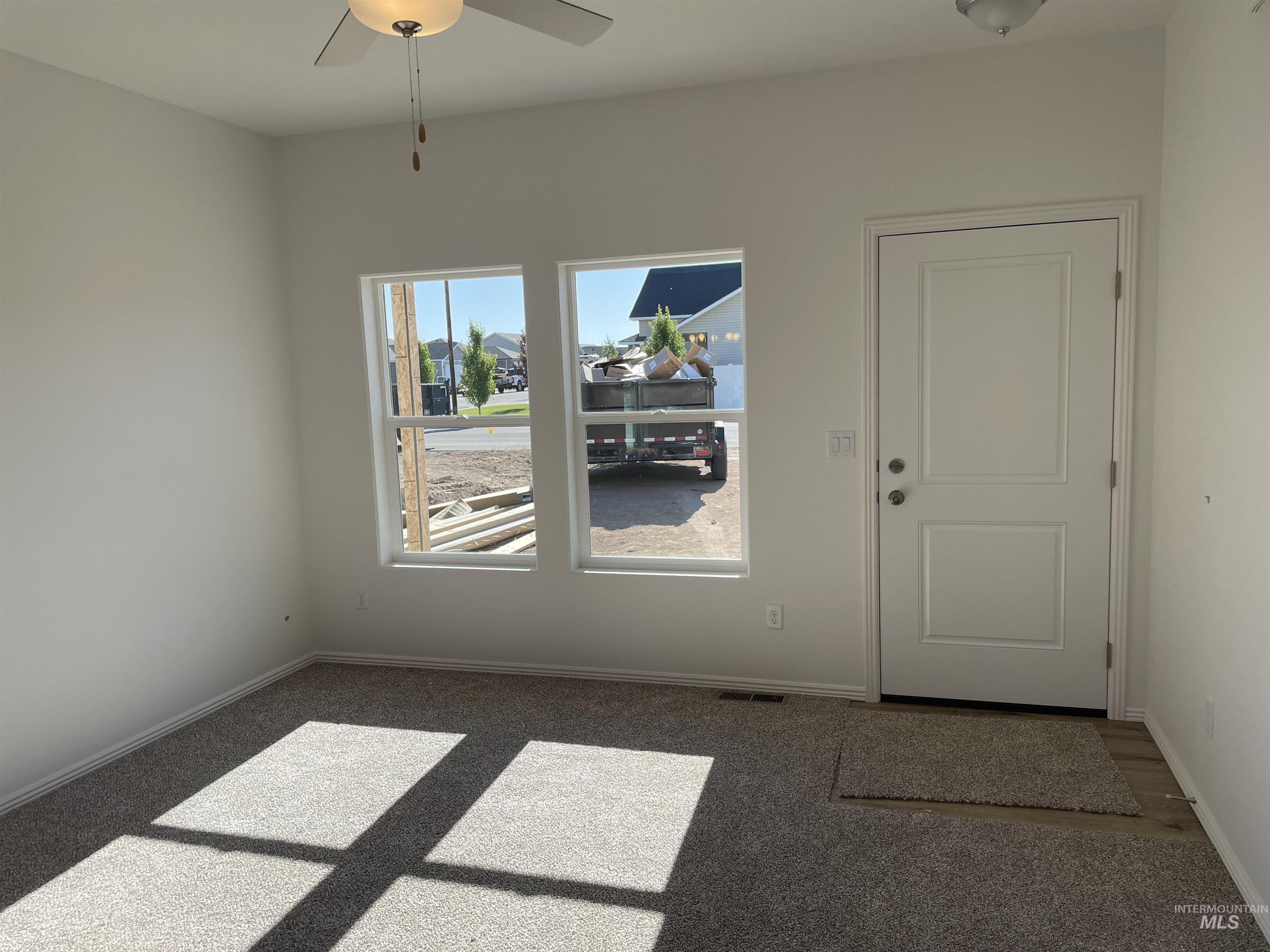 1333 Luther Road Jerome, ID 83338 - Photo 6 of 9 Room featuring two windows with white trim, light gray carpet, white walls, and a ceiling fan