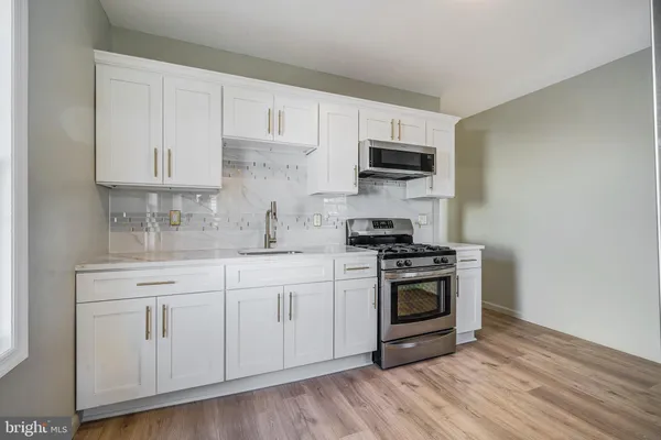a kitchen with white cabinets stainless steel appliances and wooden floor