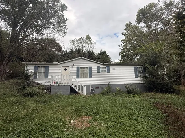 a view of a house with a yard and large trees