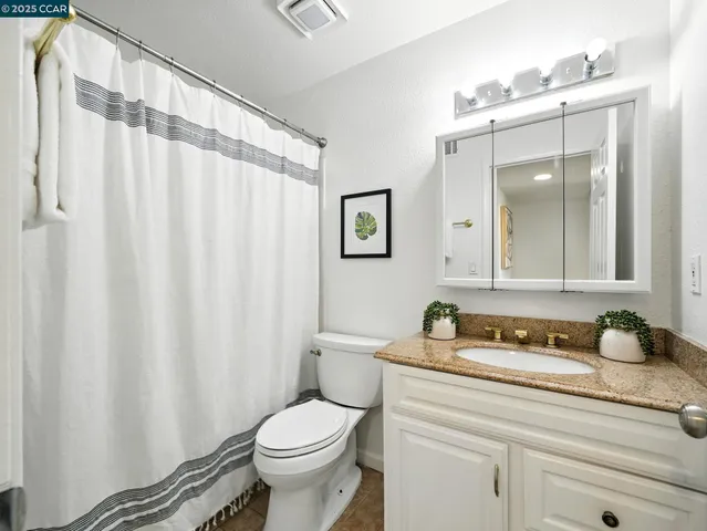 a bathroom with a granite countertop sink a toilet and a mirror