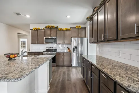 a kitchen with stainless steel appliances granite countertop a sink stove and refrigerator