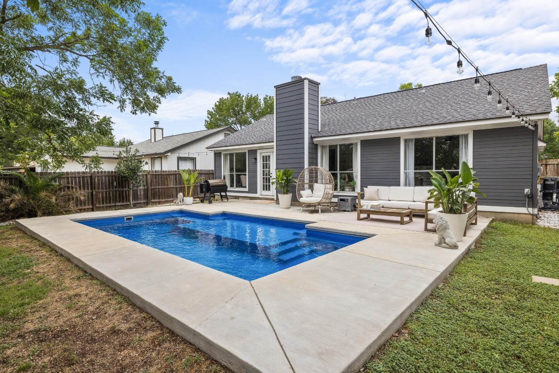 View of pool from shallow end with patio and outdoor living space.