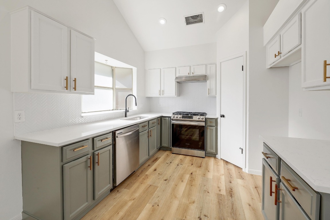 1205 Rambling Trail Cedar Park, TX 78613 - Photo 11 of 38 Kitchen with stainless steel appliances, vaulted ceiling, soft close cabinetry, deep undermount stainless sink, quartz countertops, pantry closet, and herringbone tile backsplash.