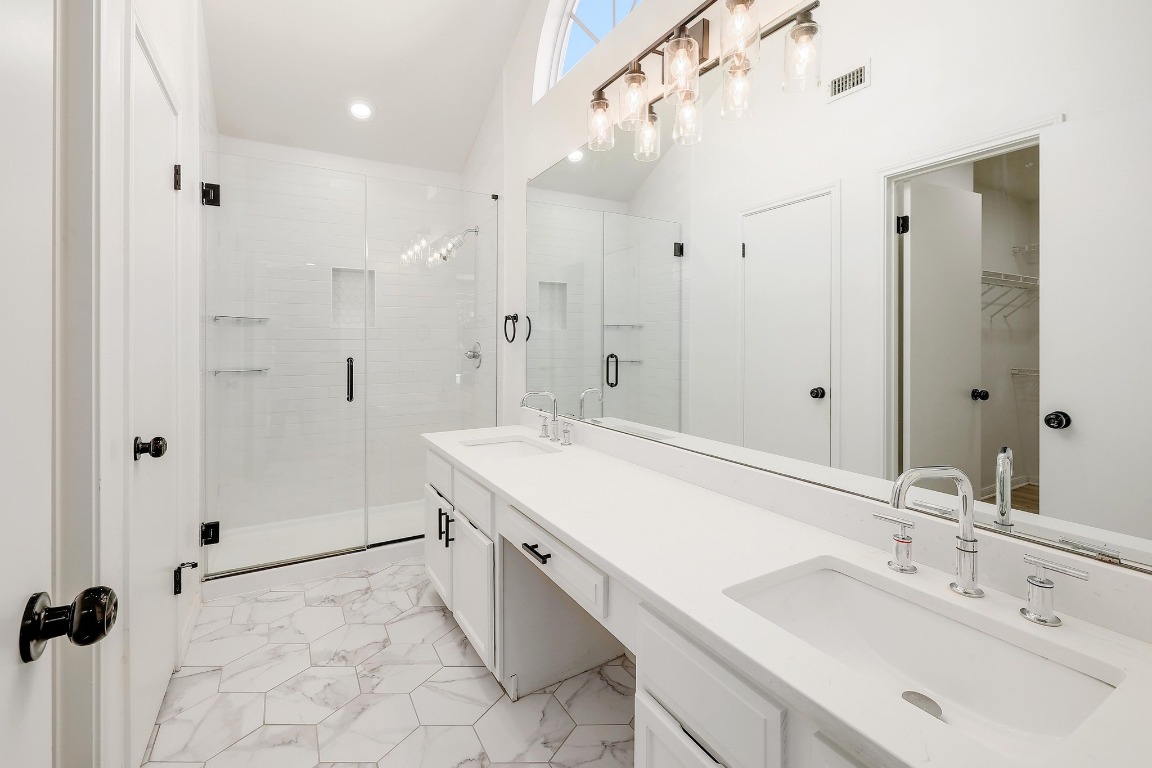 1205 Rambling Trail Cedar Park, TX 78613 - Photo 15 of 38 Primary ensuite featuring vaulted ceiling, dual vanity with powder area, oversized mirror, step-in shower tiled to the ceiling, designer tile, walk-in closet, and separate toilet room.