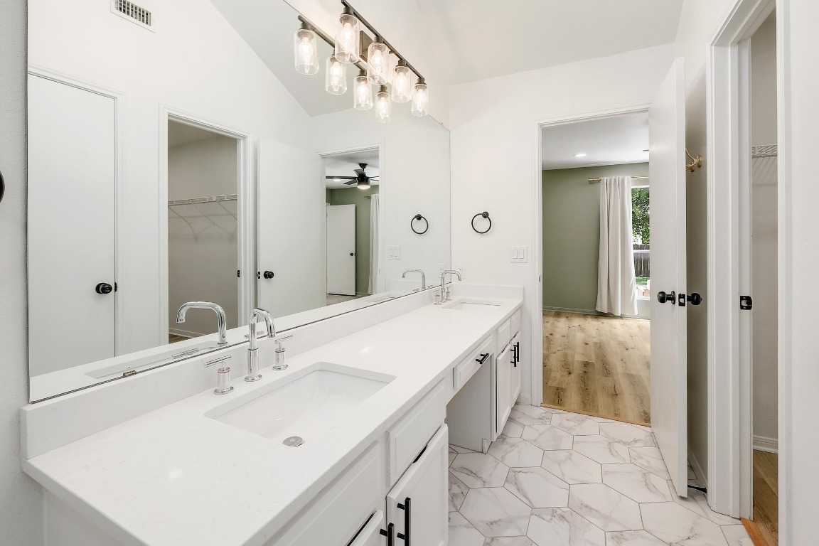 1205 Rambling Trail Cedar Park, TX 78613 - Photo 16 of 38 Primary ensuite featuring vaulted ceiling, dual vanity with powder area, oversized mirror, step-in shower tiled to the ceiling, designer tile, walk-in closet, and separate toilet room.