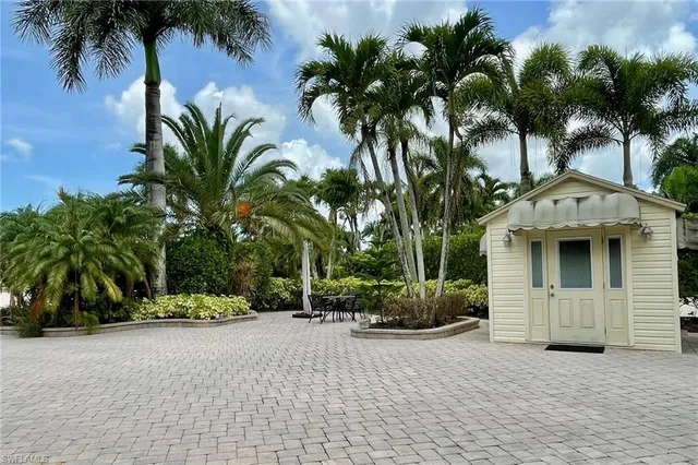 a front view of a house with a yard and palm trees