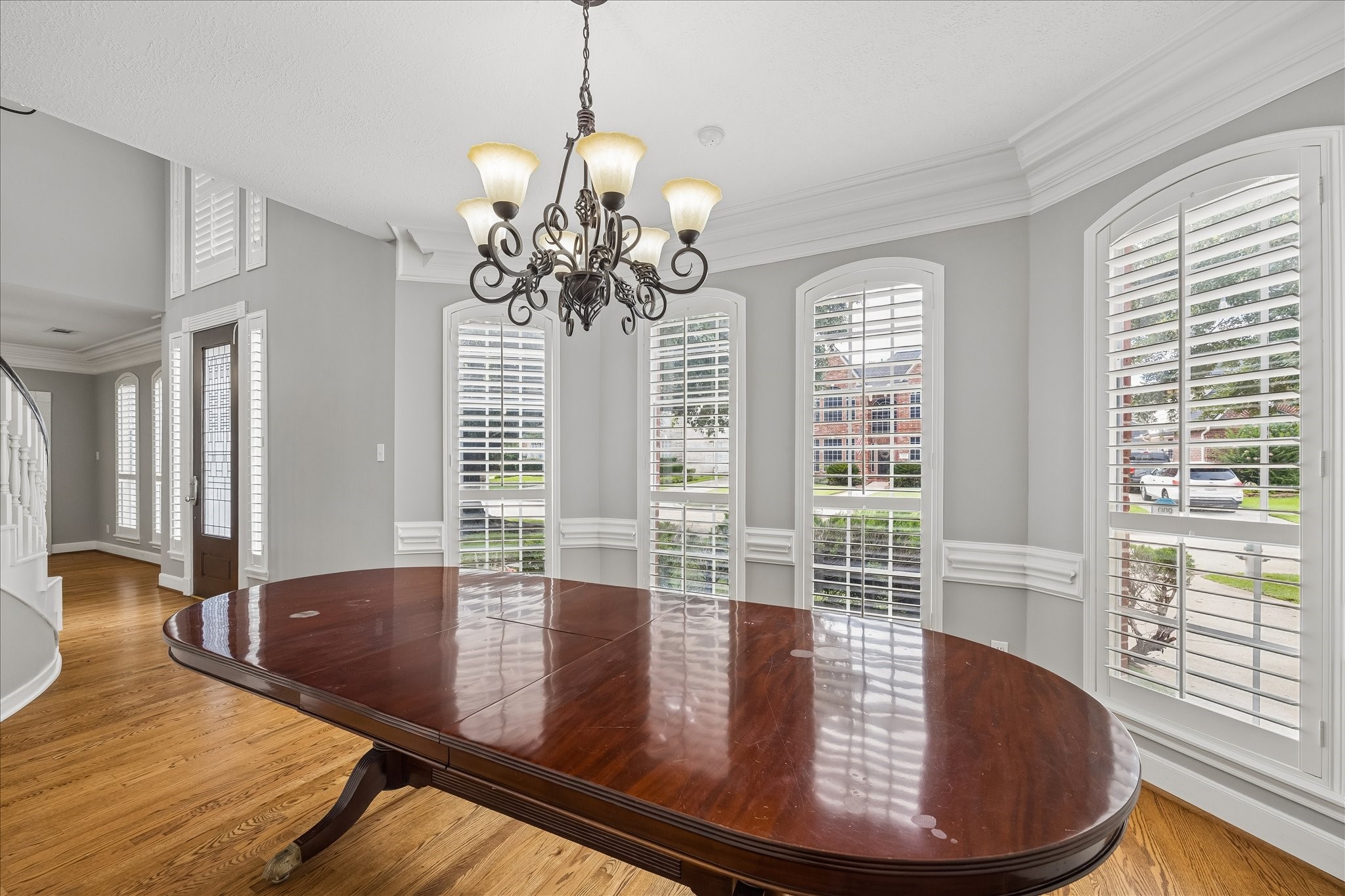 7915 Huddersfield Court Spring, TX 77379 - Photo 19 of 37 Formal dining room with hardwood floors, crown molding, chair rail detailing, and a wall of plantation-shuttered windows overlooking the front lawn.