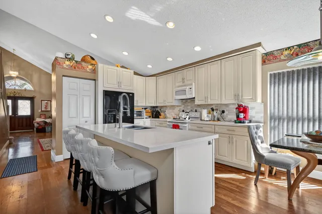 a kitchen with stainless steel appliances kitchen island granite countertop a table chairs refrigerator and sink