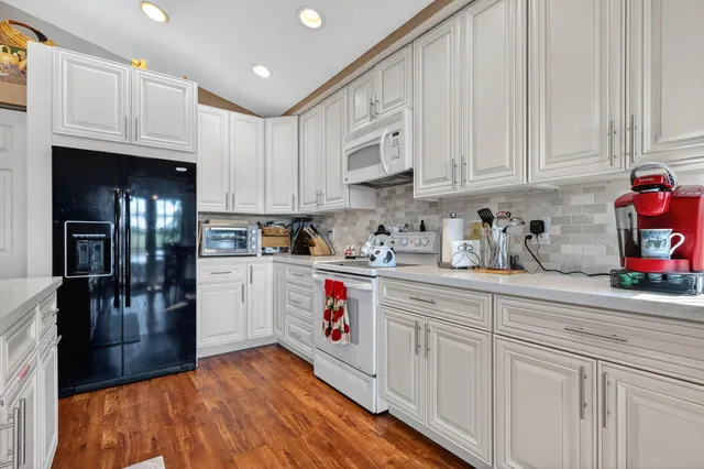 a kitchen with granite countertop white cabinets and white appliances
